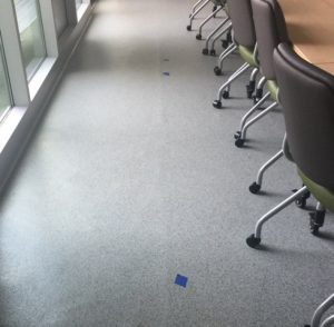 The blue tape in this photo marks a ridge in this rubber floor caused by adhesive overlap.